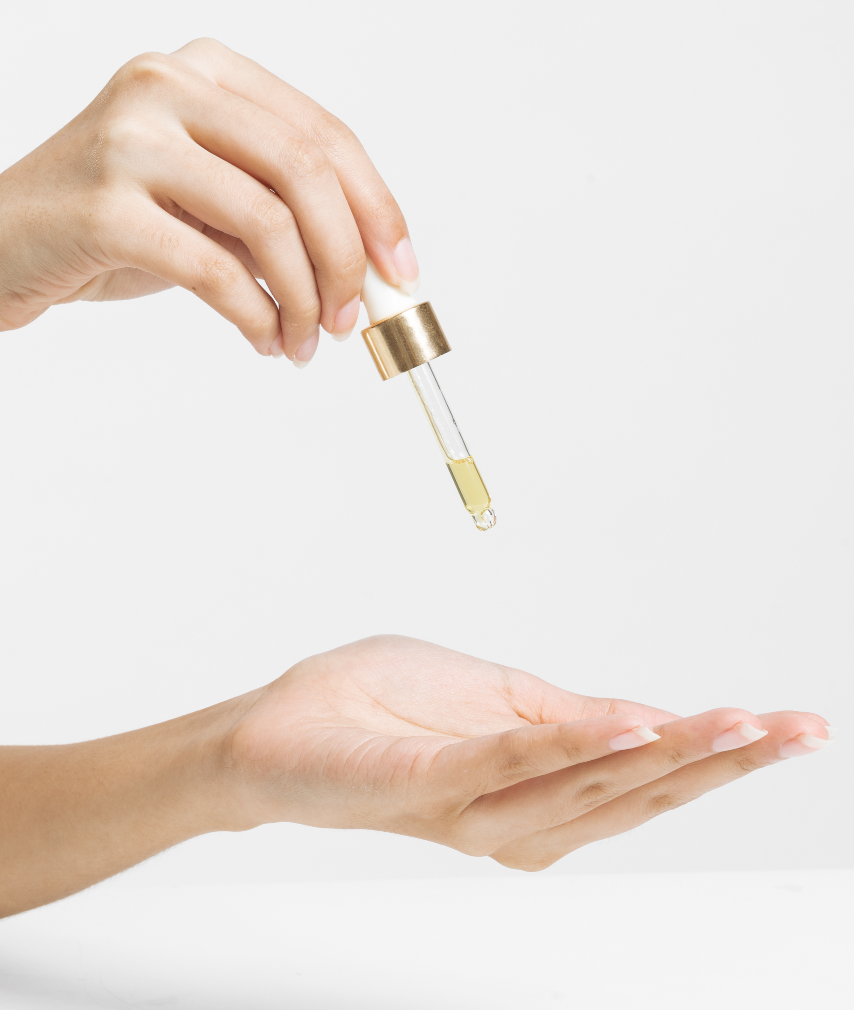 Hand holding Radiant Shield eye dropper and dropping golden serum oil into palm.