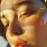 Close-up of a woman's face with a dropper applying a liquid to her skin.
